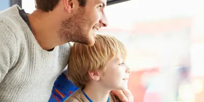 Een man en een jongen kijken uit het raam van een bus en wijzen naar bezienswaardigheden.